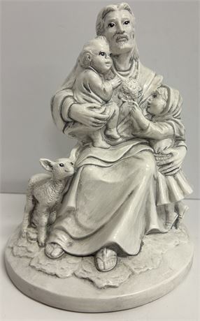 A small vintage statue of Jesus with two kids and a lamb